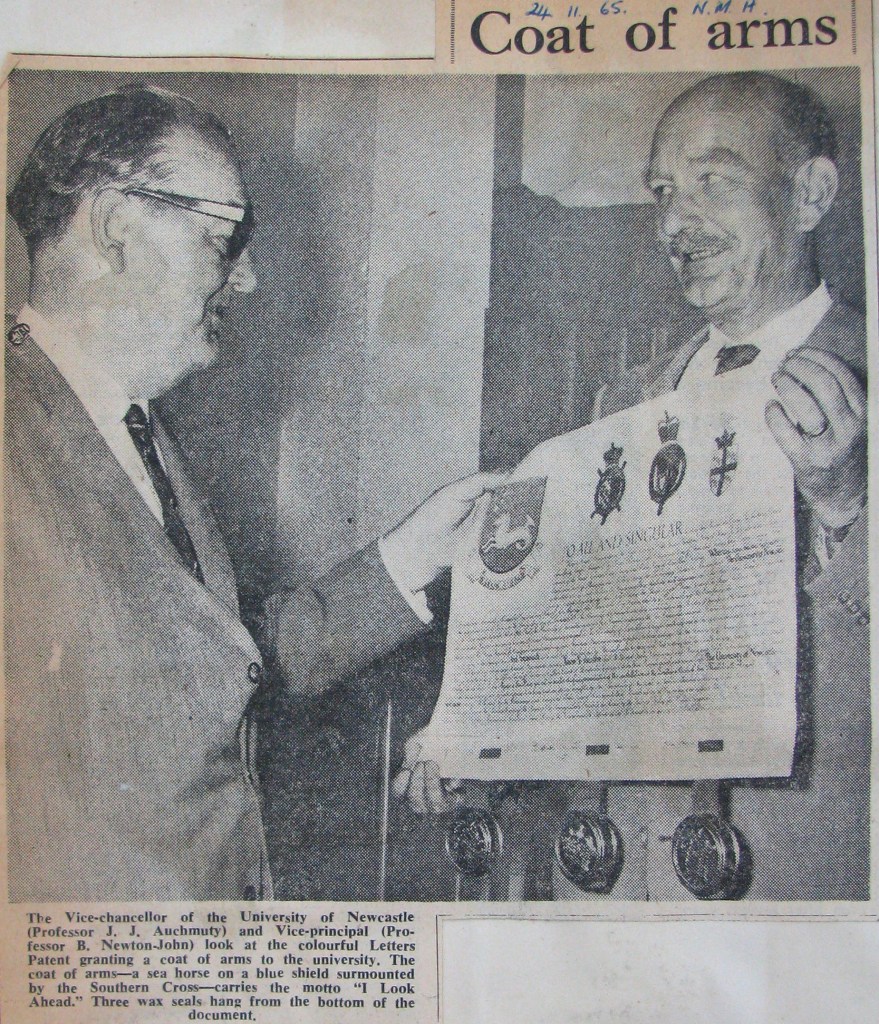 "Coat of Arms" The Vice-chancellor of the University of Newcastle (Professor J.J. Auchmuty) and Vice-principal (Professor B. Newton-John) look at the colourful Letters Patent granting a coat of arms to the university. The coat of arms - a sea horse on a blue shield surmounted by the Southern Cross - carries the motto "I Look Ahead." Three wax seals hang from the bottom of the document. Ref: Newcastle Morning Herald, 24 November 1965.